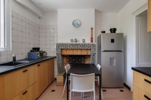 Cuisine avec cheminée du gîte Les Petits Toits à Galgon, France, avec armoires en bois et table à manger