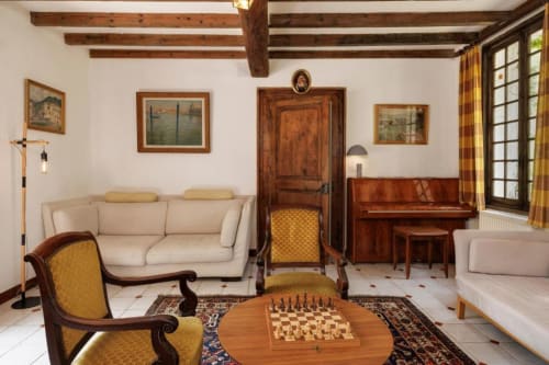Salon rustique des Petits Toits avec canapé crème, poutres bois, piano et table d'échecs à Galgon, France