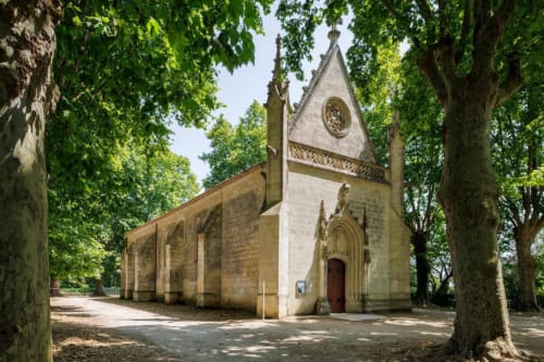 Petite chapelle en pierre historique entourée de grands arbres aux Petits Toits à Galgon, France