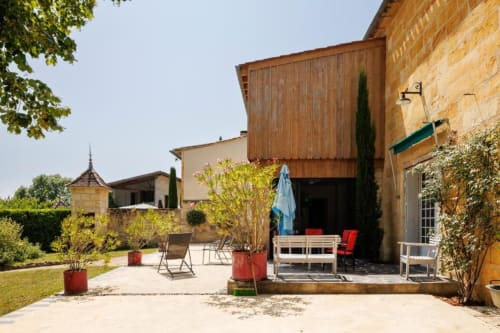Terrasse ensoleillée du gîte Les Petits Toits à Galgon, France avec mobilier de jardin et végétation luxuriante