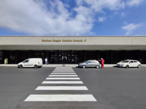 Attraversamento pedonale davanti al centro commerciale di Reggio Calabria con auto parcheggiate e cielo blu