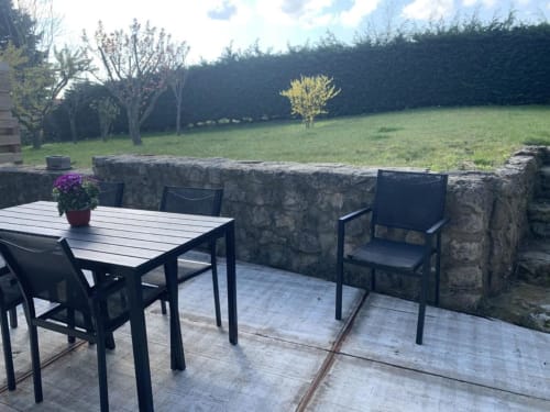 Coin salon extérieur aux Gîtes du Grand Saule à Tardinghen, avec murs en pierre, table et vue sur la campagne