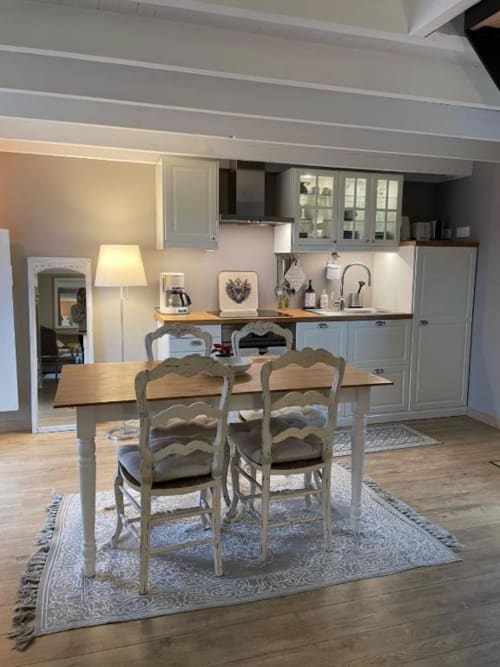 Cuisine-salle à manger du gîte aux Gîtes du Grand Saule avec table à manger, chaises rustiques, cuisine équipée et vue sur le jardin