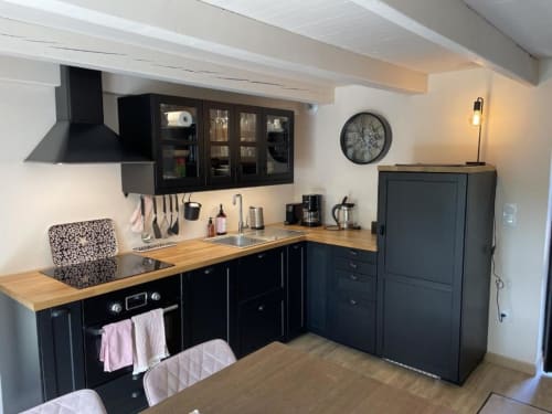 Cuisine moderne noire avec plan de travail en bois, évier, plaque de cuisson et électroménagers au gîte Les gîtes du grand saule, Tardinghen