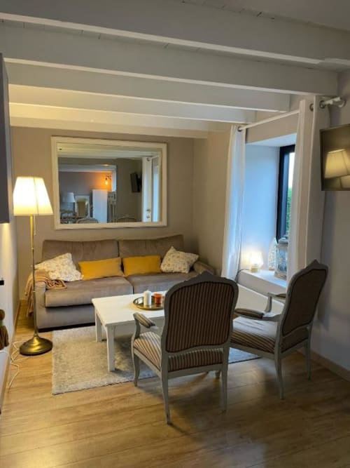 Lumineux séjour du gîte au Grand Saule avec canapé gris, fauteuils, parquet et vue sur le jardin