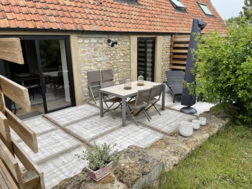 Terrasse de jardin de chaumière aux Gîtes du Grand Saule avec table à manger, mobilier extérieur et verdure luxuriante à Tardinghen.