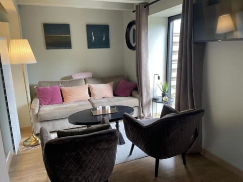 Séjour moderne aux Gîtes du Grand Saule avec canapé beige, chaises noires et vue sur le jardin à Tardinghen