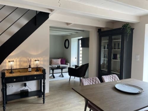 Séjour moderne avec table à manger, mobilier noir, escalier et vue sur le jardin aux Gîtes du Grand Saule