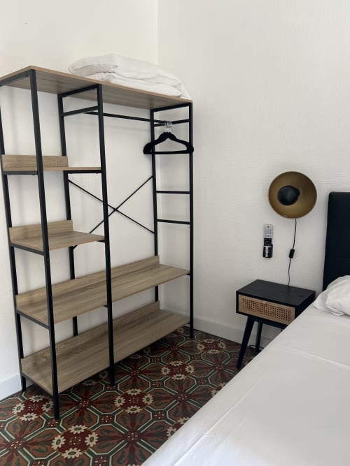 Chambre moderne avec étagères en bois et métal, table de nuit noire et tapis à motifs à l'Hôtel Les Paquebots