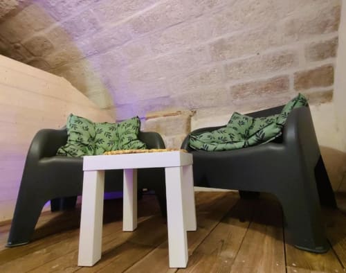 Salon moderne du Loft Le Travertin, hôtel d'Avignon, avec fauteuils noirs, coussins verts, table d'appoint blanche, parquets