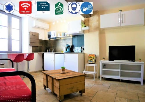 Le Travertin Studio à Avignon : salon ouvert avec kitchenette, table à manger, canapé-lit et TV dans un appartement moderne.