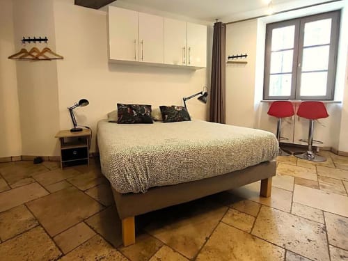 Chambre studio moderne à Oriflamme & Travertin à Avignon avec lit, kitchenette, parquet, chaises rouges et vue sur la ville