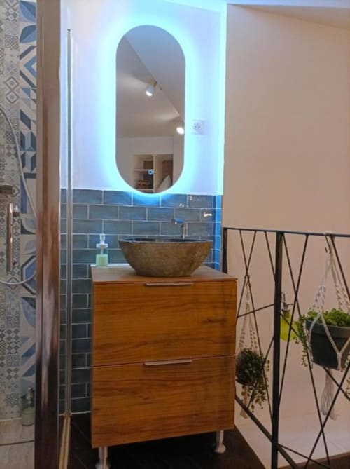 Salle de bain moderne du Loft Le Travertin à Avignon, avec miroir ovale lumineux, meuble vasque en bois, lavabo céramique et carrelage bleu