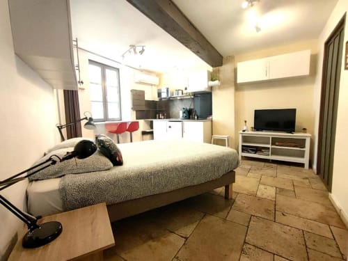 Chambre Le Travertin à Avignon : lit, kitchenette, TV et vue sur la ville depuis l'hôtel Oriflamme & Travertin