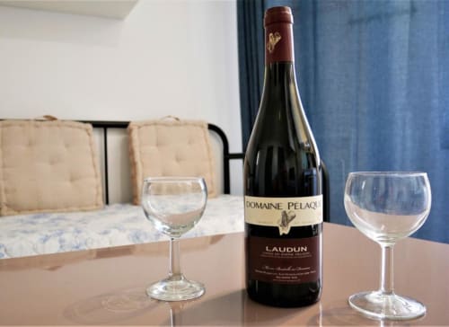 Bouteille de vin Domaine Pélaqi avec deux verres sur la table à manger chez Oriflamme & Travertin, Avignon
