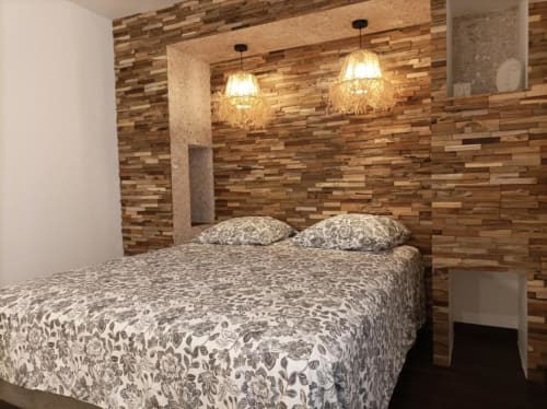 Chambre moderne avec mur d'accent en bois, literie à motifs et luminaires suspendus à l'hôtel Oriflamme & Travertin à Avignon