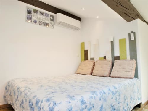 Chambre de l'appartement Le Travertin à Avignon avec dessus-de-lit floral bleu, coussins beiges et panneaux de tête de lit colorés