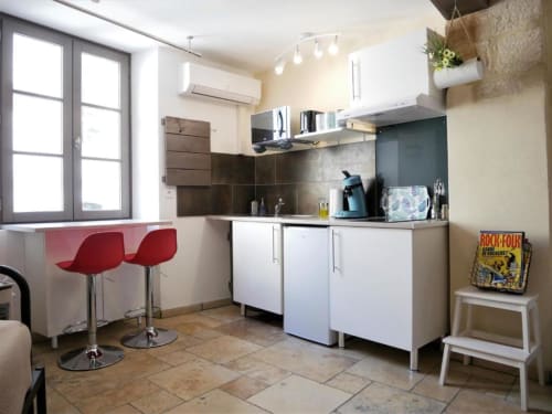 Cuisine moderne à Avignon avec armoires blanches, tabourets rouges, crédence noire et salle à manger près de la fenêtre
