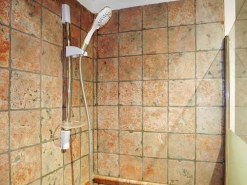 Salle de douche carrelée avec pommeau de douche manuel blanc et robinetterie en laiton au Studio Le Travertin, Avignon