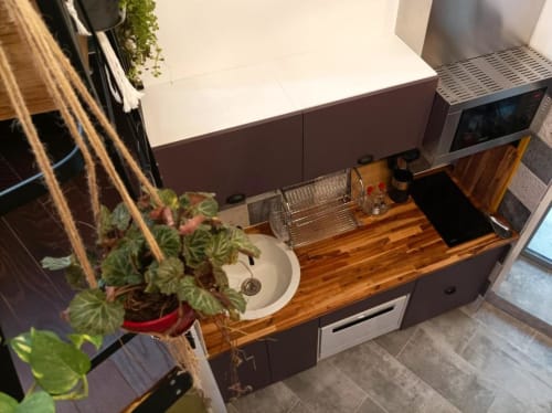 Kitchenette moderne de l'appartement Le Travertin Loft à Avignon, avec comptoirs en bois, armoires foncées et plante en pot