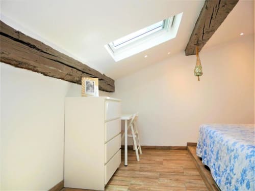 Chambre cosy sous les toits à Avignon avec poutres apparentes, lucarne, parquet et literie bleue à motifs