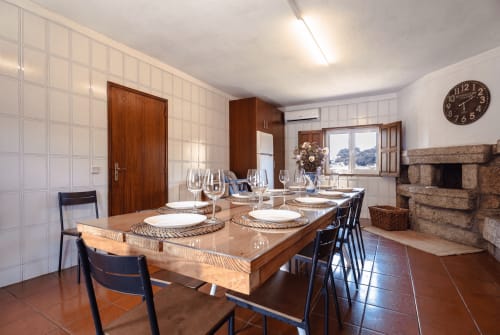Sala de jantar da Quinta de Carvalhal em Guimarães com mesa de madeira, lareira e vistas para o jardim