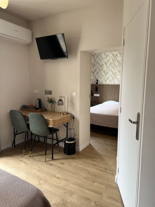 Chambre d'hôtel moderne aux Paquebots avec bureau, chaises, télévision et chambre visible par la porte à Port-Vendres