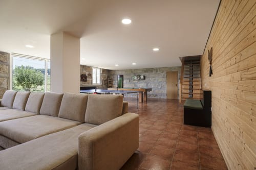 Sala de estar moderna da Quinta de Carvalhal com sofá secional bege, paredes de tijolos e vista para o jardim pelas janelas