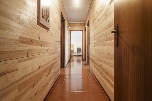 Corredor de madeira da casa rural Quinta de Carvalhal, Guimarães, levando a sala luminosa com móveis modernos