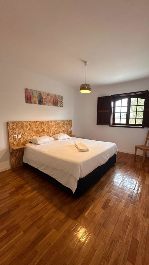 Quarto espaçoso na quinta de Carvalhal em Guimarães com cama queen, piso em madeira, luminária pendente e vistas para o jardim