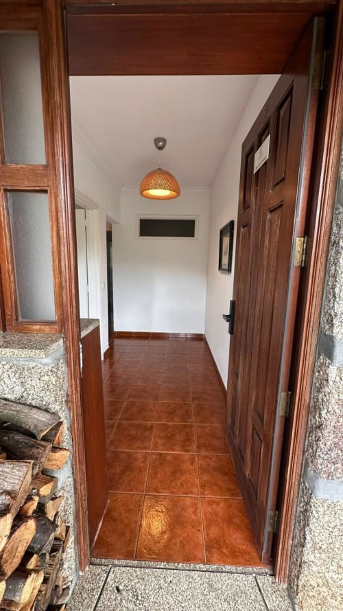 Entrada do corredor da Quinta de Carvalhal em Guimarães com azulejos de barro, portas de madeira e iluminação pendente