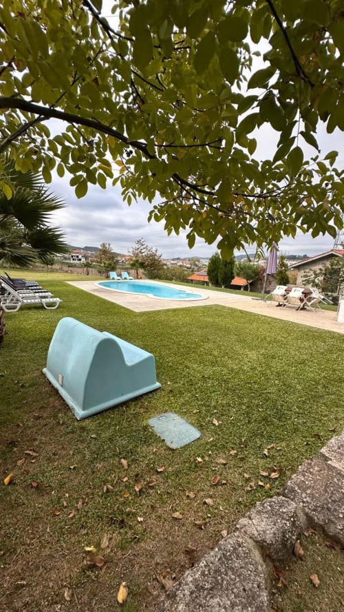 Jardim da Quinta de Carvalhal com tenda azul, piscina, espreguiçadeiras e vistas rurais perto de Guimarães