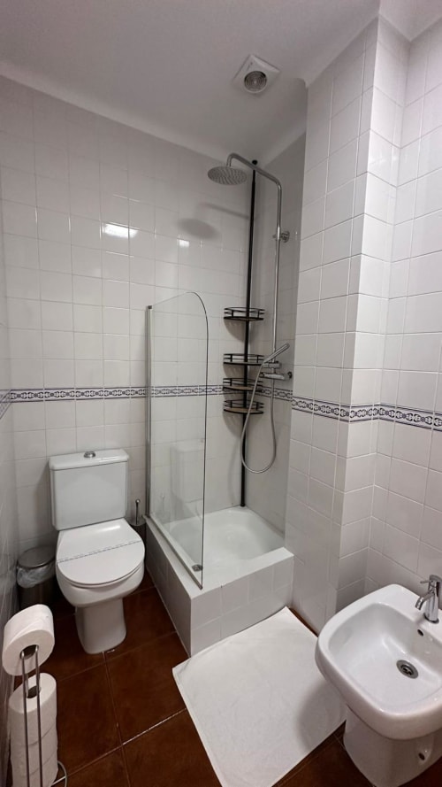 Banheiro moderno na quinta de Carvalhal com azulejos brancos, box de chuveiro, vaso sanitário, bidê e acabamentos em preto