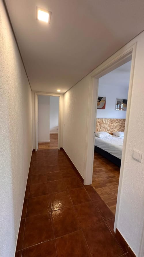 Corredor moderno com azulejos em tons de terracota conduzindo ao quarto da casinha Quinta de Carvalhal, Guimarães