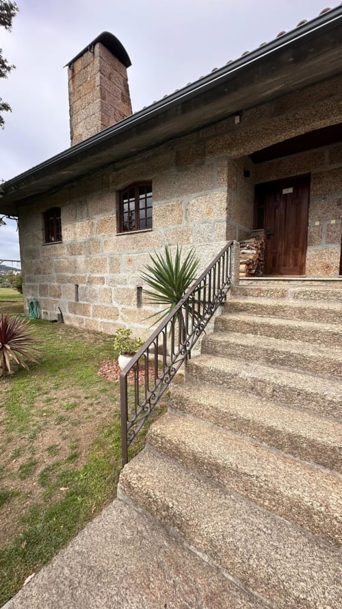 Casa de pedra na Quinta de Carvalhal em Guimarães com chaminé, varanda de ferro e jardim paisagístico