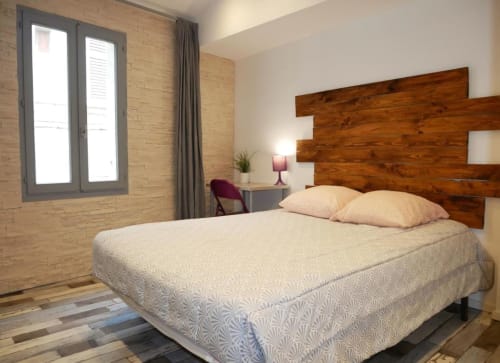 Chambre moderne de l'hôtel Oriflamme & Travertin en France avec tête de lit en bois, literie crème et murs en brique