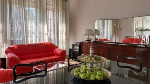 Elegante divano rosso nella sala living del B&B Il 900 di Avezzano, con espositore di frutta e mobili in legno scuro