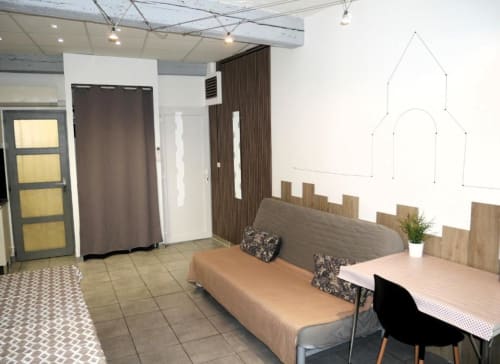 Studio Théa à Avignon : espace moderne avec lit-canapé, coin repas, kitchenette et vue sur la ville.