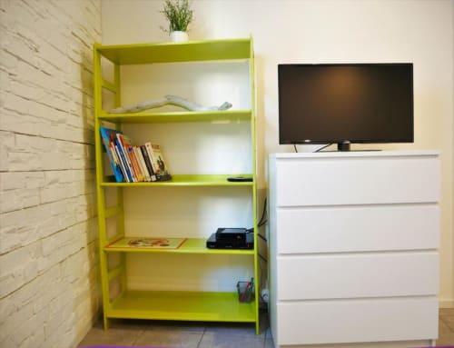 Appartement Studio Théa à Avignon avec étagères jaune vif, commode blanche et télévision écran plat murale