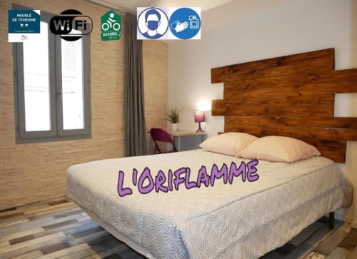 Chambre avec tête de lit en bois, literie crème, murs en brique, fenêtre, signalétique WiFi et accessibilité à l'hôtel Oriflamme