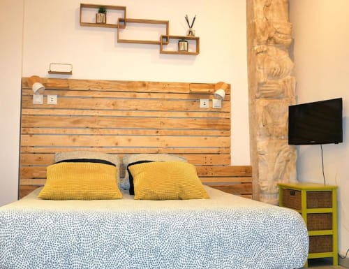 Chambre Studio Zoé à Oriflamme & Travertin à Avignon avec tête de lit en bois, oreillers jaunes et équipements modernes
