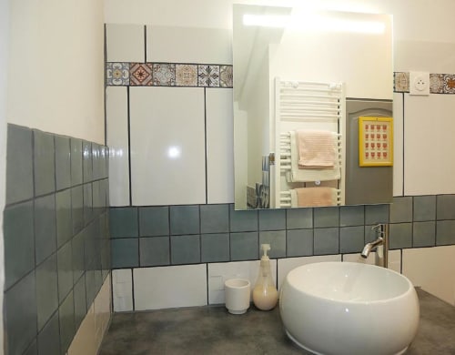 Salle de bain moderne du Studio Zoé à Oriflamme & Travertin Avignon avec lavabo blanc rond, carrelage gris et miroir décoratif