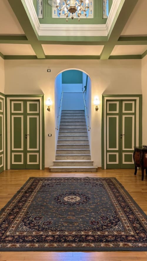 Elegante ingresso dell'Il 900 B&B ad Avezzano con porte verdi decorate, soffitto ornato e scala che conduce al piano superiore.