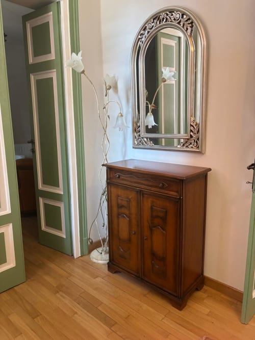 Elegante corridoio del B&B Il 900 ad Avezzano con mobile in legno, specchio ornato e fiori bianchi