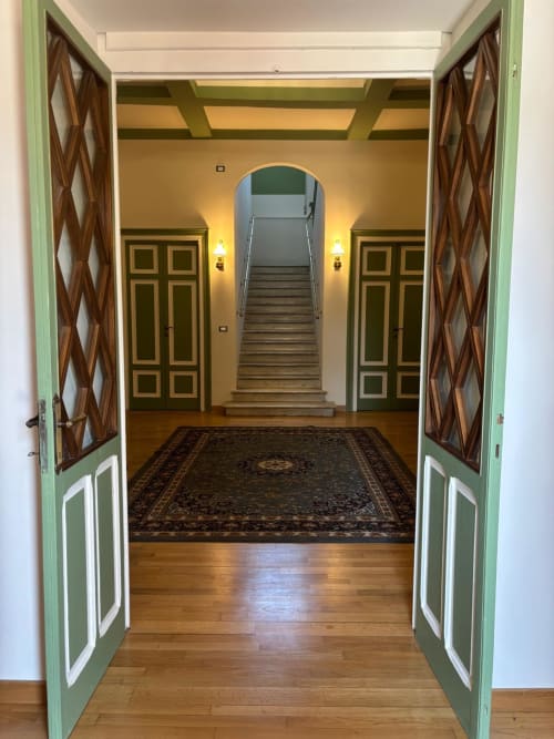 Atrio d'ingresso del B&B Il 900 ad Avezzano con doppie porte verdi, scala in legno e arredamento classico italiano