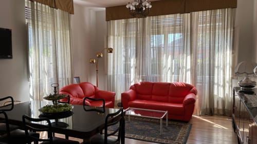 Lounge del Il 900 BnB Avezzano con divano rosso, arredi moderni e ampie finestre luminose