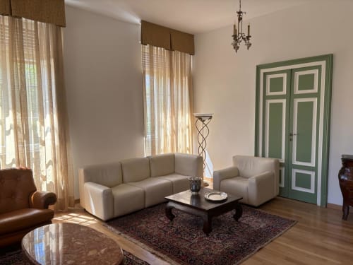 Moderno soggiorno dell'Il 900 B&B ad Avezzano con divano beige, porte verdi e illuminazione naturale