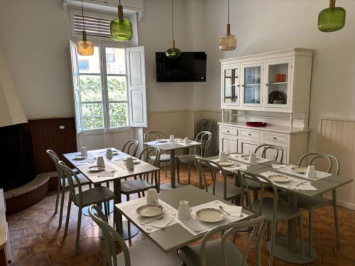 La sala da pranzo del B&B Il 900 ad Avezzano con tavoli apparecchiati, lampade a sospensione verdi e arredi classici