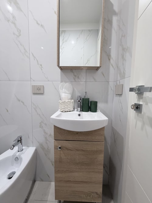 Bagno moderno a Sabò Bologna con pareti rivestite in marmo, mobile in legno, lavabo bianco e specchiera