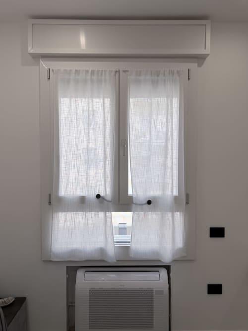 Unità di climatizzazione sotto tende leggere alle finestre della camera d'hotel Sabò Bologna con vista su cortile